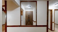 This 2-bedroom, 1-bathroom unit in Coralville, Iowa is laid out on a single floor, offering a functional and efficient use of space. The living room is a standout area, characterized by decorative exposed wood beam ceiling details, rich dark wood trim, and large vertical-blind-covered sliding doors that allow natural light to filter in. A classic wood-burning brick fireplace serves as a focal point in the living area, adding warmth and character to the space.

The galley-style kitchen is equipped with warm oak cabinetry, tile backsplash, a double-basin sink, and a white electric range, with open corner shelving providing additional storage. Tile flooring runs throughout the kitchen, while soft carpet covers the living room, hallway, and both bedrooms.

The two bedrooms are accessed via a carpeted hallway with dark wood-trimmed doors and brass hardware. The primary bedroom offers a comfortable footprint, while the second bedroom features a window with blinds that brings in natural light. Both rooms maintain the consistent dark wood trim found throughout the unit.

The bathroom includes a full tub-shower combo with a clean white surround and tiled walls. Throughout the unit, textured ceilings, consistent dark wood baseboards, and trim create a cohesive, classic aesthetic.