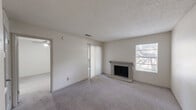 Located in Austin, TX along South Interstate 35, this one-bedroom, one-bathroom unit offers a well-organized and efficiently designed single-floor layout. The living room serves as the heart of the space, featuring a classic brick-surround fireplace as a focal point, soft wall-to-wall carpeting, and a textured ceiling. Natural light filters in through a large sliding glass door dressed with vertical blinds, which opens to an outdoor patio area, enhancing the sense of openness. A pass-through window connects the living area to the kitchen, providing convenient interaction between spaces while maintaining a defined layout. The front entryway leads directly into the main living area with easy access to the kitchen. The bedroom is a comfortable, well-proportioned room equipped with a ceiling fan and light fixture, carpeted flooring, and a sliding glass door that also accesses the outdoor patio, bringing in additional natural light. A closet provides dedicated storage. The bathroom features a full tub-shower combination with white tile surround, complemented by wood-look flooring. Neutral tones and a clean, simple palette throughout the unit create a move-in ready environment suited for practical, everyday living.