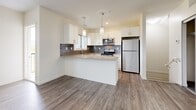 Located on K.L.O. Road in Kelowna, BC, this two-storey home offers a clean, modern design spread across two functional floors. The main floor hosts the open-concept kitchen and living area, finished with warm hardwood-style flooring throughout. The kitchen is a standout feature, showcasing crisp white cabinetry, stone-look countertops, a central island with pendant lighting, a grey subway tile backsplash, and stainless steel appliances. A window above the sink frames scenic mountain views, filling the space with natural light and a connection to the surrounding Okanagan landscape. The living area flows seamlessly from the kitchen, creating an inviting, communal atmosphere. A dedicated laundry room on the main level includes a full-size washer and dryer with overhead shelving for added convenience. Upstairs, three bedrooms offer comfortable retreats, with the primary bedroom featuring mirrored sliding closet doors and built-in shelving. Additional bedrooms are finished with plush carpeting and bright windows. Two full bathrooms, each with a soaker tub and shower surround, serve the home. A hallway and two staircases connect the floors, ensuring a practical and well-organized layout throughout.