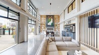 Located at 3688 Brinell St W in Columbus, Ohio, this single-level community clubhouse delivers a striking modern aesthetic with an expansive, open-concept layout. Soaring double-height ceilings define the main living and dining area, which is flooded with natural light through oversized industrial-style grid windows and large glass garage doors that open seamlessly to the outdoor terrace. Polished concrete floors run throughout, lending a sleek, contemporary feel to the entire space.

The main gathering area centers around a built-in fireplace framed by floor-to-ceiling warm wood shelving, creating a dramatic focal point. A well-appointed kitchenette with slate-blue cabinetry and modern appliances sits conveniently nearby, supporting events and everyday use. Pendant lighting and sculptural chandeliers add refined character overhead.

The entry corridor features bold deep-blue walls, dramatic pendant lighting, and a minimalist bench, setting the tone upon arrival. Large black-framed windows frame views of the landscaped courtyard outside.

Outdoors, the resort-style pool deck is a standout amenity, featuring a generously sized swimming pool with a water slide, rows of lounge chairs, a covered pergola, and an outdoor grilling station — all enclosed within a well-maintained, landscaped setting ideal for community gatherings.