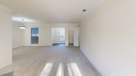 This single-story home offers a practical and comfortable layout across two bedrooms, three bathrooms, and a well-defined set of living spaces. The inviting entrance leads into a spacious living room featuring a classic fireplace with a white mantle, crown molding, and neutral carpet that carries natural light throughout the room. An adjacent dining or flex area connects seamlessly to the kitchen, which is outfitted with warm honey-toned wood cabinetry, dark granite-style countertops, a peninsula with a built-in sink, and black appliances including a range and over-the-range microwave. Durable wood-look flooring runs through the kitchen and adjoining areas. The generously sized primary bedroom includes a ceiling fan, plush carpet, and natural light from window blinds, with access to a walk-in closet featuring built-in wire shelving for organized storage. The second bedroom is similarly carpeted and well-lit. The three bathrooms include vanities with granite-style countertops and wood cabinetry, large mirrors, and at least one bathtub with a shower surround. Additional closets provide practical storage throughout the home, completing a functional and cohesive floor plan.