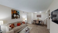 Located at 7007 Deer Path in Indianapolis, Indiana, this single-floor residence offers a thoughtfully designed layout that prioritizes comfort and functionality. The open-concept living and dining area serves as the heart of the home, creating a seamless flow between spaces ideal for both relaxing and entertaining. Soft, neutral wall tones and plush carpeting throughout lend a warm and inviting ambiance to the interior. The living area provides ample room for seating and is accented by clean white ceilings with flush lighting, contributing to a bright and airy feel. Adjacent to the living space, the dining area offers dedicated room for a full dining set, making it well-suited for everyday meals or hosting guests. Decorative wall details add a touch of personality to the space without overwhelming its understated aesthetic. A hallway visible from the main living area suggests additional rooms beyond, providing a sense of depth and privacy within the home. Overall, the residence presents a clean, move-in-ready interior with a cohesive design that balances practicality with comfort, making it an appealing option in the Indianapolis area.