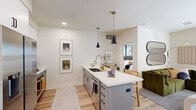 Located in Phoenix, AZ 85014, this single-floor 2-bedroom, 2-bathroom residence offers a thoughtfully designed layout with modern finishes throughout. Light wood-style flooring flows through the main living areas, creating a cohesive and contemporary aesthetic.

The kitchen is a standout feature, centering around a spacious island with a white quartz countertop, undermount sink, and seating for casual dining. Gray cabinetry, pendant lighting, and stainless steel appliances—including a French door refrigerator—complete the space. The kitchen opens directly to the living room, which benefits from natural light through a glass exterior door and windows with blinds.

Both bedrooms are carpeted and well-proportioned, with the primary bedroom offering a ceiling fan and natural light from a large window. Each bedroom is served by its own walk-in closet, both fitted with multi-tier hanging rods and shelving for organized storage.

The two bathrooms are finished with gray vanity cabinetry, white quartz countertops, backlit mirrors, and light wood-style flooring. One bathroom features a walk-in glass shower, while the other includes a combined shower and tub. Both maintain a clean, spa-inspired aesthetic consistent with the home's overall modern design.