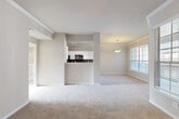 This well-appointed two-story home offers five bedrooms and two full bathrooms across a thoughtfully designed layout. The main level features an open-concept kitchen and living room combination, where a peninsula with granite countertops separates the two spaces. The kitchen is outfitted with white cabinetry, a classic tile backsplash, stainless steel appliances including a refrigerator, electric range, and microwave, along with hardwood-style flooring. The adjoining living area is carpeted and benefits from ample natural light through large windows dressed with blinds, and is accented by crown molding and a pendant light fixture. A carpeted staircase with a white handrail leads to the upper level, which houses the majority of the bedrooms, hallways, and closets. The generously sized primary bedroom features crown molding, a ceiling fan, a large window, and direct access to a walk-in closet with built-in shelving. Additional bedrooms are carpeted with neutral wall tones. The bathrooms include a tub-shower combination with white tile surround and wood-style flooring. Two closets provide ample storage, and the property also includes an attached garage with an automatic opener.