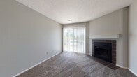 Located at 7200 Chadwood Ln in Dublin, Ohio, this single-floor home offers a thoughtfully arranged layout with a blend of carpet and hardwood-style flooring throughout. The living area serves as the centerpiece of the home, featuring a tile-surround fireplace with a clean white mantel and a large sliding glass door fitted with vertical blinds that invite natural light and provide views of the outdoors. A textured ceiling carries through the common areas, contributing to the home's consistent aesthetic.

Adjacent to the living area, the layout opens toward a dining or transitional space that connects to the kitchen. The kitchen is equipped with warm wood cabinetry, granite-style countertops, an electric range with overhead ventilation, and a full-size refrigerator, providing functional cooking and storage space.

The bedroom areas are carpeted and well-lit by multiple windows with blinds, offering views of the surrounding greenery. One bedroom includes access to a walk-in closet with shelving. The bathroom features a wide vanity with wood cabinetry and granite-style countertops, a large mirror, a tub-shower combination, and hardwood-style flooring, creating a polished and practical space overall.
