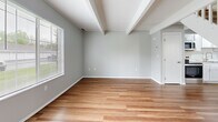 Located at 1400 Fuller Ct in Lancaster, Ohio, this two-story home offers a thoughtfully laid-out floor plan across two levels. The main floor features a combined kitchen and living area finished with warm hardwood-style flooring and exposed beam detailing on the ceiling. The kitchen stands out with crisp white shaker cabinetry, marble-look countertops, a peninsula with additional counter seating, and a full suite of stainless steel appliances including a range, microwave, dishwasher, and refrigerator. Track lighting overhead enhances the bright, open feel of the space. A white-railed staircase leads to the upper level, where both bedrooms are finished with plush carpeting, soft gray walls, and ceiling fans with integrated lighting. Each bedroom benefits from natural light through blinded windows. The primary bedroom offers generous closet storage, including a built-in double closet and an open shelving unit. The full bathroom is clean and functional, featuring a soaker tub and shower combination with a curved curtain rod and light wood-style flooring. A hallway connects the upstairs rooms efficiently. Throughout the home, a consistent neutral color palette and modern fixtures create a cohesive, move-in-ready aesthetic.