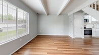 Located at 1400 Fuller Ct in Lancaster, Ohio, this two-story home offers a thoughtfully laid-out floor plan across two levels. The main floor features a combined kitchen and living area finished with warm hardwood-style flooring and exposed beam detailing on the ceiling. The kitchen stands out with crisp white shaker cabinetry, marble-look countertops, a peninsula with additional counter seating, and a full suite of stainless steel appliances including a range, microwave, dishwasher, and refrigerator. Track lighting overhead enhances the bright, open feel of the space. A white-railed staircase leads to the upper level, where both bedrooms are finished with plush carpeting, soft gray walls, and ceiling fans with integrated lighting. Each bedroom benefits from natural light through blinded windows. The primary bedroom offers generous closet storage, including a built-in double closet and an open shelving unit. The full bathroom is clean and functional, featuring a soaker tub and shower combination with a curved curtain rod and light wood-style flooring. A hallway connects the upstairs rooms efficiently. Throughout the home, a consistent neutral color palette and modern fixtures create a cohesive, move-in-ready aesthetic.