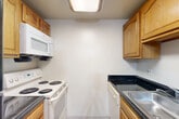 Located at 1527 Heather Hollow Cir in Silver Spring, MD, this two-bedroom, two-bathroom residence offers a practical and comfortable single-floor layout. The kitchen is efficiently designed with warm oak cabinetry, dark countertops, wood-look flooring, and white appliances including a coil-top electric range, over-the-range microwave, and dishwasher, alongside a black refrigerator. The space flows naturally from the kitchen into the carpeted living areas. Both bedrooms are carpeted and filled with natural light from windows with blinds that overlook greenery outside. The spacious primary bedroom features direct access to a private en-suite bathroom and a dedicated walk-in closet equipped with wire shelving systems, providing ample storage. Both bathrooms are finished with light tile flooring and include a full tub-shower combination with white tile surrounds. The second bedroom is a comfortable, well-proportioned room with a window view of the surrounding neighborhood. Throughout, neutral wall tones and clean lines create a calm, functional atmosphere, making this a well-organized and move-in ready home.