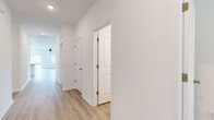 Located at 129 Mainland Lakes Dr in Bluffton, SC, this single-story home offers a well-organized floor plan featuring four bedrooms, two bathrooms, and a dedicated laundry room. Light wood-look flooring runs throughout, complementing the crisp white walls and creating a clean, cohesive aesthetic across every room. The open-concept kitchen and living area serves as the heart of the home, where a granite-topped center island with an integrated sink anchors the kitchen. White shaker cabinetry, a subway tile backsplash, and stainless steel appliances — including a refrigerator, range, and microwave — complete the kitchen's functional and stylish design. The living room benefits from sliding glass doors that open to the backyard, inviting natural light and outdoor views into the space, accompanied by a ceiling fan overhead. The primary bedroom is generously sized, featuring a ceiling fan and ample room for furnishings. Additional bedrooms are bright and well-proportioned, each with windows that frame views of the surrounding neighborhood. The bathrooms are finished with white vanities and wood-look flooring, with one bathroom featuring a glass-enclosed walk-in shower. A dedicated laundry room houses a full-size washer and dryer with overhead shelving. A connecting hallway with panel doors and recessed lighting ties all spaces together seamlessly.