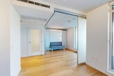 Located in Vancouver's desirable West End neighborhood, this thoughtfully designed one-bedroom, one-bathroom unit makes excellent use of its compact footprint through smart, flexible architecture. Warm light hardwood flooring flows consistently throughout the entire space, creating a cohesive and inviting atmosphere.

The open-concept living area is defined by large floor-to-ceiling windows that frame striking views of the Vancouver skyline and surrounding mountains, flooding the interior with natural light. Innovative frosted glass sliding panel partitions divide the living room from the bedroom, offering flexible privacy without sacrificing the sense of openness. The bedroom features built-in cabinetry for streamlined storage.

The kitchen is well-appointed with warm wood-toned lower cabinetry, crisp white upper cabinets, stainless steel appliances including a built-in oven, and track lighting overhead. A freestanding island with drawer storage serves as a versatile workspace and dining surface. A dedicated in-unit laundry closet with stacked washer and dryer adds everyday convenience.

The bathroom is finished in clean white subway tile, featuring a soaker tub with a glass panel and a dual-function rainfall and handheld shower system. A private balcony extends the living space outdoors, offering open-air access to sweeping city and water views. The unit's modern, minimalist aesthetic is consistent throughout.