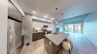 Located in the heart of Seattle's Belltown neighborhood, this modern residence offers four bedrooms and two bathrooms across a thoughtfully designed single-floor layout. The open-concept kitchen serves as a centerpiece, featuring a large island with a quartz-style countertop, an undermount sink with pendant lighting above, stainless steel appliances, and a two-tone cabinet design with dark lower and white upper cabinetry framed by a tile backsplash. Light hardwood flooring flows throughout the main living areas, complementing the contemporary aesthetic. A distinctive architectural detail is the exposed concrete ceiling and structural columns, lending an industrial-modern character throughout the space. The primary bedroom offers a generous footprint with large windows that invite natural light and urban views of the Seattle skyline. Additional bedrooms are carpeted and bright, with some featuring floor-to-ceiling windows and outdoor views. Both bathrooms are finished with large-format tile flooring, modern vanities with stone countertops, and sleek fixtures. The primary bathroom stands out with a dual-sink vanity and expansive windows overlooking the city. Built-in cabinetry in the living area provides ample storage while maintaining clean, modern lines throughout.