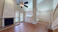 This two-story residence offers a well-designed layout across two levels, combining functional living spaces with notable architectural details. The main living area immediately impresses with its dramatic vaulted ceilings that rise to a striking height, enhanced by a ceiling fan with light fixture and abundant natural light from sliding glass doors that lead to an outdoor deck. A wood-burning fireplace with a raised tile hearth serves as a focal point, while hardwood-style flooring flows throughout the main level, adding warmth and continuity.

The galley-style kitchen is efficiently arranged with white cabinetry, ample counter space, white appliances including a range and refrigerator, a sink, and a window that brings in natural light. A pass-through connects the kitchen to the living area, maintaining an open feel.

Both bedrooms are generously proportioned, carpeted for comfort, and equipped with ceiling fans. The primary bedroom features direct access to a full bathroom with a long vanity offering dual sinks, abundant cabinet storage, and a separate tub/shower combination. A spacious walk-in closet with wire shelving provides excellent storage. The second bedroom is served by an additional full bathroom. Stairs connect the two floors, completing this thoughtfully arranged home.