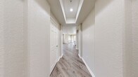 Located in San Diego's Mission Valley area, this single-story residence offers a thoughtfully designed layout with two bedrooms, two bathrooms, a combined kitchen and living room, a dedicated laundry area, two closets, and three hallways connecting the spaces seamlessly.

The kitchen is a standout feature, showcasing white shaker cabinetry extending to the ceiling, a large waterfall-edge quartz island with an undermount sink, stainless steel appliances including a gas range, microwave, and refrigerator, and recessed lighting — all set against light wood-style flooring that flows throughout the home.

The living area benefits from abundant natural light through large windows and sliding door access to an outdoor space. Both bedrooms are generously proportioned, featuring ceiling fans, wide windows with views of the surrounding neighborhood, and the same warm wood-tone flooring. The primary bedroom connects directly to a bathroom equipped with a walk-in closet featuring built-in shelving, a white vanity with stone countertop, and a full tub/shower combination.

The second bathroom mirrors the clean, all-white aesthetic with a tiled tub/shower surround. An in-unit laundry area houses a modern front-loading washer. Neutral warm-gray walls and consistent flooring throughout lend the home a cohesive, contemporary feel.