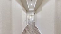 Located in San Diego's Mission Valley area, this single-story residence offers a thoughtfully designed layout with two bedrooms, two bathrooms, a combined kitchen and living room, a dedicated laundry area, two closets, and three hallways connecting the spaces seamlessly.

The kitchen is a standout feature, showcasing white shaker cabinetry extending to the ceiling, a large waterfall-edge quartz island with an undermount sink, stainless steel appliances including a gas range, microwave, and refrigerator, and recessed lighting — all set against light wood-style flooring that flows throughout the home.

The living area benefits from abundant natural light through large windows and sliding door access to an outdoor space. Both bedrooms are generously proportioned, featuring ceiling fans, wide windows with views of the surrounding neighborhood, and the same warm wood-tone flooring. The primary bedroom connects directly to a bathroom equipped with a walk-in closet featuring built-in shelving, a white vanity with stone countertop, and a full tub/shower combination.

The second bathroom mirrors the clean, all-white aesthetic with a tiled tub/shower surround. An in-unit laundry area houses a modern front-loading washer. Neutral warm-gray walls and consistent flooring throughout lend the home a cohesive, contemporary feel.