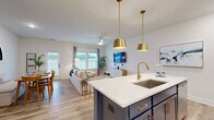Located at 9100 Bluedale Road in Charlotte, NC, this two-story home offers a thoughtfully designed layout spread across two floors. Light hardwood flooring flows throughout, complementing the clean white walls and creating a bright, cohesive aesthetic.

The main floor opens into an inviting hallway that leads to the open-concept kitchen, dining, and living areas. The kitchen is a standout feature, showcasing white shaker cabinetry, stainless steel appliances, a mosaic tile backsplash, and a bold navy blue island topped with white quartz countertops and finished with gold pendant lighting and hardware. The living room receives ample natural light through large windows and features a ceiling fan, while the dining area offers a cozy nook setting accented by an arched mirror. A half bath is conveniently located on this floor.

Upstairs, the primary bedroom is generously sized with its own walk-in closet fitted with wire shelving systems. Two additional bedrooms are well-proportioned and bright, each with natural light from exterior windows. The home includes five bathrooms in total, ensuring comfort and convenience for all occupants. A staircase with warm wood treads and white railings connects both levels. Three closets provide ample storage throughout the home.
