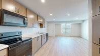 Located at 550 W Lake St in Minneapolis, MN, this well-appointed unit offers four bedrooms and two full bathrooms across a generously sized single-floor layout. The open-concept kitchen and living area serves as the heart of the home, featuring light wood-tone cabinetry with matte black hardware, white countertops, stainless steel appliances including a built-in microwave, electric range, and dishwasher, and a double-basin sink. Recessed lighting illuminates the space, which flows seamlessly into the expansive living area with windows that bring in natural light and views of the surrounding neighborhood. Light hardwood-style flooring runs throughout the main living areas and all four bedrooms, creating a cohesive, modern aesthetic. Each bedroom is comfortably sized, with large windows and clean white walls offering a bright, neutral canvas. The primary bedroom includes a sliding closet door for added convenience. Both bathrooms are finished with light tile flooring, warm wood vanities with white countertops, and black accent hardware. One bathroom features a full tub-shower combination with white subway tile surround. The overall design is clean, contemporary, and move-in ready.