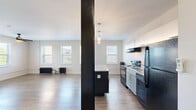 Located at 310 W Sixth St, Unit 403 in Royal Oak, MI, this single-floor unit offers an efficient and well-appointed layout comprising a combined kitchen and living area alongside one full bathroom. The open-plan living and kitchen space is anchored by warm wood-look flooring that runs throughout, lending a cohesive and inviting feel. Multiple windows fitted with horizontal blinds line the walls, flooding the interior with natural light and offering views of the surrounding Royal Oak cityscape. Distinctive cast-iron radiators serve as both a functional heating source and a charming architectural nod to classic building design. The kitchen features a central island with a granite-look countertop, pendant lighting overhead, white upper cabinetry, and black appliances including a range, dishwasher, and refrigerator. A ceiling fan in the main living area adds comfort and airflow. Sliding closet doors provide practical storage. The bathroom is finished with tile flooring, a tub-shower combination with dark tile surround, a white vanity, and a window for natural ventilation. The unit's neutral color palette and clean lines create a bright, functional living environment in the heart of downtown Royal Oak.