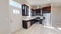 This single-floor residence offers a clean, contemporary design highlighted by light wood-look tile flooring that flows consistently throughout the entire space, creating a cohesive and inviting atmosphere. The kitchen serves as a functional centerpiece, outfitted with rich dark espresso cabinetry featuring glass-front upper doors, light stone countertops, a subway tile backsplash, and a full suite of stainless steel appliances including a gas range, built-in microwave, dishwasher, and French door refrigerator. Multiple windows allow natural light to fill the kitchen, enhancing its bright and polished character. The open living area is generously sized, with large windows fitted with blinds that bathe the room in natural light, and a paneled entry door with transom window adds architectural interest. The bedrooms are comfortably scaled with neutral warm-toned walls, recessed lighting, and vaulted ceilings in select rooms that lend a sense of added volume. Two full bathrooms serve the home, each featuring a tub-shower combination and clean white fixtures. One bathroom includes a pedestal sink and a window for natural ventilation, while the second is accessed via a private door. Throughout, the home maintains a neutral, move-in-ready aesthetic ideal for comfortable everyday living.