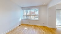 This three-storey residence on Victoria Park Avenue in Toronto is thoughtfully designed across three distinct levels, offering a well-organized layout with two bedrooms and two bathrooms. Light-toned hardwood flooring runs throughout the main and upper levels, creating a warm, cohesive aesthetic that complements the clean white walls and recessed pot lighting found in every room.

The ground level features a spacious living area with a wood-baluster staircase and a small window that brings in natural light. The main floor hosts an open-concept kitchen and living space, where the kitchen stands out with sleek flat-front white cabinetry, dark quartz countertops, a grey tile backsplash, a gas cooktop island with a stainless steel range hood, a built-in oven, and integrated dishwasher.

The upper floor accommodates both bedrooms, including a well-proportioned primary bedroom with a large window framing neighbourhood views. A second bedroom features a built-in sliding-door closet. Two bathrooms serve the residence: one is a bright, spa-like full bathroom with a glass-enclosed shower, soaker tub, and floating vanity; the other is a clean, compact three-piece with neutral tile finishes.
