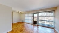 This single-floor residence offers a practical and efficient layout across three bedrooms, two bathrooms, and a combined living and dining area. The kitchen features dark espresso cabinetry extending to the upper walls, light countertops, wood-look vinyl flooring, and a full suite of white appliances including a refrigerator, electric range, and sink — all illuminated by a flush overhead fluorescent light. The open living and dining area is carpeted and filled with natural light, with a ceiling fan overhead and sliding glass doors that open to an outdoor balcony, offering views of surrounding greenery. Each of the three bedrooms is carpeted and features wide windows that allow natural light and outdoor views, with at least two of the bedrooms equipped with dedicated closets offering shelving for organized storage. The primary bedroom includes a ceiling fan and its own closet. Both bathrooms are finished with subway tile wainscoting, vanity mirrors with lighted fixtures, and clean white fixtures throughout — one featuring a shower/tub combination. Five closets distributed throughout the unit provide generous storage capacity, complemented by a hallway that connects the rooms in a logical flow.