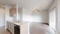 This single-floor, 2-bedroom, 2-bathroom residence offers a thoughtfully designed layout that maximizes functionality and comfort. The open-concept kitchen flows seamlessly into the living and dining areas, creating a cohesive and social living space. The kitchen is equipped with taupe cabinetry, light granite-style countertops, black appliances including a range, refrigerator, dishwasher, and over-range microwave, all set on durable wood-style flooring. A peninsula with a double sink connects the kitchen to the adjacent dining area, which features a pendant light fixture and a wall-unit HVAC.

The living room is bright and airy, enhanced by a ceiling fan, wood-style flooring, and a sliding glass door that opens to a private balcony overlooking the surrounding neighborhood. Both bedrooms are carpeted and offer natural light through blinded windows. Each bedroom includes a closet, and the primary bedroom features dual windows for added brightness. The two bathrooms are finished with wood-tile flooring, granite-style vanity countertops, taupe cabinetry, and clean white fixtures. One bathroom includes a walk-in shower, while the other features a towel bar and open layout. Neutral tones and consistent finishes throughout give the space a clean, cohesive aesthetic.