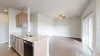 This single-floor, 2-bedroom, 2-bathroom residence offers a thoughtfully designed layout that maximizes functionality and comfort. The open-concept kitchen flows seamlessly into the living and dining areas, creating a cohesive and social living space. The kitchen is equipped with taupe cabinetry, light granite-style countertops, black appliances including a range, refrigerator, dishwasher, and over-range microwave, all set on durable wood-style flooring. A peninsula with a double sink connects the kitchen to the adjacent dining area, which features a pendant light fixture and a wall-unit HVAC.

The living room is bright and airy, enhanced by a ceiling fan, wood-style flooring, and a sliding glass door that opens to a private balcony overlooking the surrounding neighborhood. Both bedrooms are carpeted and offer natural light through blinded windows. Each bedroom includes a closet, and the primary bedroom features dual windows for added brightness. The two bathrooms are finished with wood-tile flooring, granite-style vanity countertops, taupe cabinetry, and clean white fixtures. One bathroom includes a walk-in shower, while the other features a towel bar and open layout. Neutral tones and consistent finishes throughout give the space a clean, cohesive aesthetic.