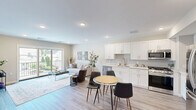 Located at 228 Morris Ave in Long Branch, NJ, this thoughtfully designed 1-bedroom, 1-bathroom residence offers a clean, modern aesthetic across a single floor. The open-concept layout seamlessly connects the kitchen, dining area, and living room, creating a bright and functional shared space bathed in natural light. The kitchen is outfitted with crisp white shaker cabinetry extending to the ceiling, a subway tile backsplash, light quartz countertops, and a full suite of stainless steel appliances including a gas range, built-in microwave, dishwasher, and French door refrigerator. Light wood-tone flooring runs throughout, lending warmth and continuity. The living room is anchored by large sliding glass doors that open to a private balcony overlooking the neighborhood, flooding the space with natural light and outdoor views. The bedroom is a well-proportioned retreat featuring a window with neighborhood views, a dedicated closet, and continued wood-tone flooring. The full bathroom features large-format tile flooring, a white vanity with storage, and a tub-shower combination. A dedicated in-unit laundry room with a full-size washer and dryer adds everyday convenience. Recessed lighting throughout completes the polished, contemporary feel of this well-appointed residence.