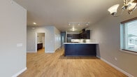 Located at 1605 Meijer Dr in Greenville, Michigan, this thoughtfully designed two-bedroom, two-bathroom single-floor unit offers a contemporary living experience with high-quality finishes throughout. The open-concept layout seamlessly connects the living area to the kitchen, which serves as the centerpiece of the home. The kitchen is outfitted with rich dark espresso cabinetry, light quartz countertops, a white subway tile backsplash, and a full suite of stainless steel GE appliances, including a refrigerator, range, microwave, and dishwasher. A peninsula with a built-in sink provides additional workspace and casual seating. Track lighting above the kitchen and recessed lighting throughout enhance the bright, clean aesthetic. Warm-toned luxury vinyl plank flooring flows continuously across the main living spaces and bedrooms, adding cohesion and ease of maintenance. The living and dining area is bathed in natural light from large windows and a sliding glass door, which is complemented by a ceiling fan and chandelier. Both bathrooms feature dark cabinetry with quartz countertops and brushed nickel fixtures; one includes a soaking tub and shower combo, while the other offers a walk-in shower with glass enclosure and tile flooring. A dedicated in-unit laundry room houses a full-size washer and dryer with built-in shelving above.