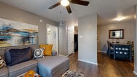 This single-floor residence offers a thoughtfully designed layout that maximizes comfort and functionality throughout. The living room serves as the heart of the home, featuring a classic tiled fireplace, wood-look flooring, and a ceiling fan overhead. A set of sliding glass doors dressed with vertical blinds fills the room with natural light while providing access to an outdoor area. The galley-style kitchen is efficiently arranged with white cabinetry, granite-look countertops, a double basin sink, and black appliances, offering ample storage and workspace along its length. A dedicated in-unit laundry space houses a stacked washer and dryer alongside a hanging rod, adding everyday convenience. The bedroom is a restful retreat with carpeted flooring, a ceiling fan, and a window that welcomes natural light. The full bathroom is clean and functional, featuring a granite-look vanity with a white basin, a medicine cabinet, and a shower/tub combination with a decorative curtain. Throughout the unit, wood-look flooring ties the common areas together, while neutral gray walls and textured ceilings create a cohesive and comfortable living environment.