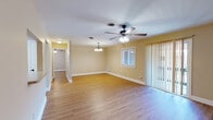 Located at 2 Hollandale Ln in Clifton Park, NY, this single-floor residence offers a thoughtfully laid-out living space with a warm, neutral color palette throughout. The entryway features clean tile flooring that transitions into rich hardwood-style floors found across the main living and bedroom areas, creating a cohesive and inviting atmosphere.

The open living and dining area is generously sized, bathed in natural light from a large sliding glass door that leads to an outdoor space, complemented by a window and fitted with vertical blinds. A ceiling fan with integrated lighting and an elegant chandelier-style pendant fixture add both function and character to the room.

The kitchen is well-appointed with warm wood cabinetry, stone-look countertops, a tile backsplash, and a full suite of stainless steel appliances including a range, microwave, and dishwasher. Tile flooring and under-cabinet lighting complete the practical yet attractive design.

The bedrooms are comfortable and well-lit, each with hardwood-style flooring and ceiling fans. One room provides convenient access to an in-unit laundry area. The bathroom features a full tub-shower combination with tile surround detailing. Clean white trim and millwork are consistent throughout, lending the entire home a polished, well-maintained appearance.