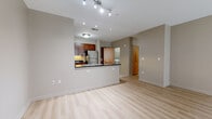 Located at 206 Market St in Westlake, Ohio, this single-floor unit offers a thoughtfully designed open-concept layout finished in a neutral, warm palette throughout. Light hardwood flooring runs through the main living areas, anchoring the space with a clean, modern aesthetic. The living area is generously proportioned and receives natural light through large windows that overlook the surrounding building exterior.

The kitchen is a standout feature, showcasing rich cherry wood cabinetry extending to the ceiling, dark granite countertops, and a full suite of stainless steel appliances including a gas range, built-in microwave, and refrigerator. A peninsula with a dark granite surface provides additional prep space and separates the kitchen from the living area. Tile flooring grounds the kitchen zone.

The bedroom is carpeted and well-lit by a large window, offering a comfortable, quiet retreat. The primary bathroom features a glass-enclosed walk-in shower, tile flooring, and direct access to a spacious walk-in closet equipped with wire shelving on multiple walls. A second full bathroom includes a soaking tub, cherry vanity, and a round mirror. A dedicated laundry room with full-size washer and dryer completes the functional layout of this well-appointed unit.