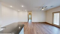 Located at 1125 Country Club Road in Lake Charles, Louisiana, this single-story home offers a thoughtfully designed floor plan with three bedrooms, two bathrooms, and an abundance of closet space throughout. Warm wood-look flooring runs through the main living areas, complemented by crisp white walls and recessed lighting that create a clean, bright ambiance.

The open-concept living and dining area flows seamlessly from the kitchen, which serves as the centerpiece of the home. The kitchen features a large island with dark granite countertops, white shaker-style cabinetry, a double sink, and black appliances including a gas range, microwave, and refrigerator. A ceiling fan overhead and natural light from nearby windows add to the welcoming feel.

A central hallway connects the bedrooms, each carpeted for comfort and equipped with generous closet space — including walk-in closets fitted with wire shelving. The primary bedroom is notably spacious. Both bathrooms include granite-topped vanities, large mirrors, and wood-look flooring.

The dedicated laundry room provides added convenience, complete with washer and dryer units and upper white cabinetry for storage. A balcony offers an outdoor retreat, rounding out this well-equipped home.