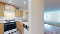 Located at 18547 Plummer St in Northridge, Los Angeles, this one-bedroom, one-bathroom unit offers a well-organized single-floor layout that makes efficient use of its space. The open-concept kitchen and living area serves as the heart of the unit, with the kitchen featuring warm honey-toned wood cabinetry, light stone-finish countertops, a gas range, dishwasher, and a double sink. A peninsula counter with recessed lighting separates the kitchen from the living area, providing additional prep space and a natural transition between the two zones. Wood-style vinyl flooring runs throughout the kitchen and entry hallway, adding durability and a clean aesthetic. The living room is spacious and bright, with plush carpet, white walls, and a window that allows natural light to fill the room. The bedroom is a comfortable size, also carpeted, with windows providing additional natural light and ample room for standard furnishings. A dedicated closet offers convenient storage. The bathroom is finished with wood-style flooring, a wood-toned vanity with a stone-finish countertop, and a full-size tub and shower combination. A hallway connects the main living spaces, contributing to a logical and functional flow throughout the unit.