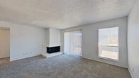 This single-floor, 1-bedroom, 1-bathroom residence offers a thoughtfully organized layout that maximizes functionality and comfort. The combined kitchen and living room serves as the heart of the home, featuring plush carpet flooring, a textured ceiling, and a striking white-painted wood-burning fireplace as a central focal point. Large sliding glass doors open to an outdoor area, flooding the living space with natural light, while an additional side window enhances brightness throughout. The galley-style kitchen is efficiently designed with wood-look flooring, white cabinetry, and black appliances including a refrigerator, range, and dishwasher, keeping cooking and storage neatly organized. A hallway connects the living areas to the private bedroom, which is comfortably sized and features carpet flooring, a large window for natural light, and direct access to a spacious walk-in closet outfitted with dual shelving on both sides. The full bathroom includes wood-look flooring, a white vanity with sink, and a tub-shower combination highlighted by bold, stone-patterned tile surround. A dedicated hallway and closet round out this well-appointed residence, providing practical storage and ease of movement throughout.
