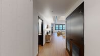 Located at The Victor in St. Louis, MO, this two-bedroom, two-bathroom residence combines industrial loft character with contemporary design across a single, well-appointed floor. Warm hardwood flooring runs throughout the space, complemented by crisp white walls, exposed ductwork, and structural beams that nod to the building's architectural heritage.

A welcoming entryway corridor opens into the living area, which is anchored by large black-framed windows that flood the room with natural light and frame views of the surrounding cityscape. An exposed brick accent wall adds texture and warmth to the living space.

The kitchen features white shaker cabinetry extending to the ceiling, stainless steel appliances including a full-size refrigerator, range, microwave, and dishwasher, along with a stylish tile backsplash and a breakfast bar for casual dining.

Both bedrooms offer a calm, neutral palette with high ceilings and hardwood flooring. The primary bathroom is appointed with a dark-framed glass shower enclosure, a dark wood vanity, and white tile, while the second bathroom features a full soaking tub with white subway tile surround and matte black fixtures throughout. The result is a cohesive, modern urban residence with thoughtful detailing at every turn.