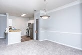 Located at 1400 Mall of Georgia Blvd in Buford, Georgia, this single-floor residence offers a well-organized, functional layout designed for comfortable everyday living. The open-concept living and dining area is finished with plush carpeting and neutral-toned walls, creating a warm and inviting atmosphere. Crown molding with tray ceiling detailing adds an architectural touch to the main living space, lending it a polished, refined character.

The kitchen is a standout feature, designed in a galley-style configuration with crisp white cabinetry, light countertops, and a classic subway tile backsplash. Stainless steel appliances — including a refrigerator, range, and built-in microwave — provide a sleek, modern finish, while wood-look flooring grounds the space with a clean, durable surface. A pass-through counter connects the kitchen to the living area, enhancing the open flow of the home.

The bedrooms are carpeted and generously proportioned, each offering ceiling fans and ample wall space. A dedicated in-unit laundry area adds everyday convenience. The bathroom is equipped with a soaking tub and shower combination, fully tiled surround, and classic chrome fixtures, offering a clean and functional retreat. Overall, the residence presents a cohesive, neutral palette throughout, making it a versatile and move-in-ready space.