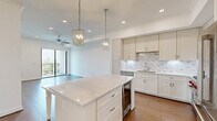 Located in Houston's desirable 77098 zip code, this 1-bedroom, 1-bathroom residence offers a thoughtfully designed open-concept layout with premium finishes throughout. Wide-plank hardwood flooring flows seamlessly from the living area into the kitchen, creating a cohesive and inviting atmosphere.

The gourmet kitchen is a standout feature, showcasing dramatic marble-veined quartz countertops on both the expansive island and perimeter surfaces, crisp shaker-style cabinetry, a marble subway tile backsplash with under-cabinet lighting, and a full suite of stainless steel appliances including a gas range, built-in microwave, refrigerator, and dishwasher. Elegant chrome pendant chandeliers illuminate the island, adding a refined touch.

The living area is bright and airy, benefiting from floor-to-ceiling windows and a sliding glass door that opens to a private balcony with sweeping views of the Houston skyline and surrounding greenery. A ceiling fan enhances comfort throughout.

The spacious bedroom features large windows capturing abundant natural light and city views, complemented by a ceiling fan and direct access to a dedicated closet. The bathroom is appointed with marble-look tile flooring, a marble-surround soaking tub and shower, a white shaker vanity with quartz countertop, and a large backlit mirror.