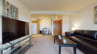 Located at 2815 Beltline Frontage Rd in Madison, WI, this single-floor unit offers a practical and comfortable layout across several well-defined living spaces. The living room is generously sized, featuring neutral carpet flooring, a ceiling fan, and a large window that allows natural light to fill the space. Black leather seating and a central coffee table create a functional and cohesive seating arrangement, while a wall-mounted flat-screen TV completes the entertainment area.

The kitchen is outfitted with warm-toned wood cabinetry extending to the ceiling, offering ample storage. It includes a full suite of white appliances—refrigerator, gas range, and over-the-range microwave—alongside a double sink and tile flooring. A compact dining area with a bar-height table and stools sits adjacent to the kitchen, making the space efficient for everyday use.

Two carpeted bedrooms each include windows for natural light and ceiling fixtures. One features a ceiling fan, while both provide adequate space for standard bedroom furnishings. The full bathroom includes a wood-framed vanity with white countertop, tile flooring, and a shower/tub combination with a curtain enclosure.
