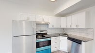 This thoughtfully renovated single-floor unit offers a clean, modern aesthetic throughout. The kitchen is a standout feature, outfitted with crisp white shaker-style cabinetry, dark granite countertops, and a classic white subway tile backsplash. Stainless steel appliances—including a refrigerator, electric range, and dishwasher—complete the functional and stylish space. Recessed and flush-mount lighting brightens the area, while a window allows natural light to flow into the adjoining living space.

Light gray wood-look flooring runs continuously throughout the unit, lending a cohesive and contemporary feel. The open layout connects the kitchen to the living area seamlessly, with clean white walls that enhance the sense of brightness and space. A hallway leads to well-proportioned rooms, each featuring generous windows that invite natural light and offer views of the surrounding neighborhood.

The bathroom is finished with large-format marble-style floor tiles, a gray vanity with a white countertop, and a window for natural ventilation. The overall design is minimal and neutral, creating a versatile backdrop suitable for a variety of interior styles. Throughout the unit, crisp white trim and paneled doors provide polished finishing touches.