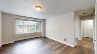 Located in Portland's NE neighborhood, this single-floor, 3-bedroom, 1-bathroom unit offers a practical and well-appointed layout across a compact but efficiently utilized footprint. Warm-toned luxury vinyl plank flooring runs throughout the living areas and bedrooms, creating a cohesive and easy-to-maintain interior.

The living room is a standout space, featuring a large picture window that floods the room with natural light and frames views of surrounding greenery. A flush-mount light fixture and a textured ceiling add character, while a built-in wall vent provides in-unit climate control.

The kitchen is functionally designed with white cabinetry, a coil-burner electric range, ample counter space, and a double basin sink beneath a window. The marble-look tile flooring ties in cleanly with the white finishes throughout.

Three well-sized bedrooms each offer neutral walls, LVP flooring, and individual windows — several overlooking lush tree canopies — providing a calm, nature-connected atmosphere. The primary bedroom includes double closet doors for generous storage. The shared full bathroom features a tub/shower combo with tiled surround and the same elegant marble-look tile flooring found in the kitchen. Clean white trim and neutral tones throughout give the unit a fresh, move-in-ready feel.
