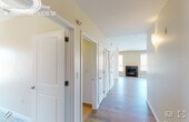 This single-floor residence offers a carefully considered layout that balances comfort and functionality throughout. The open living area is a standout, anchored by a sleek fireplace with a dark surround and framed by multiple windows that fill the space with natural light. A full-width sliding glass door opens to a private balcony overlooking a sweeping, verdant hillside — a serene backdrop that brings the outdoors in. Light hardwood flooring runs through the main living areas, adding warmth and continuity.

The kitchen is well-equipped with rich, dark wood cabinetry extending to the ceiling for ample storage, complemented by stainless steel appliances including a gas range, microwave, refrigerator with ice maker, and dishwasher. Light countertops and a window above the sink round out the functional and attractive workspace.

A hallway connects the bedrooms and bathrooms, lined with white paneled doors and wall sconces. The bedrooms feature plush carpeting and generous closet space. The bathrooms are finished with warm wood vanities, stone-tone countertops, full tub and shower combinations clad in large-format tile, and accessibility grab bars. A separate half bath with a pedestal sink serves as a convenient powder room.