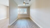 Located at 205 Hollis Rd in Charlotte's dynamic Dilworth neighborhood, this thoughtfully designed unit offers a efficient, modern layout across a single floor. Light wood-tone flooring flows throughout, creating a cohesive and airy feel.

The galley-style kitchen is a standout feature, equipped with stainless steel appliances — including a refrigerator, stove, and dishwasher — complemented by sleek gray shaker cabinetry with glass-front upper cabinets, dark countertops, a subway tile backsplash, and a deep undermount sink. A built-in desk or bench area adjacent to the kitchen adds a practical, multi-use element to the living space.

The living area is bright and open, benefiting from natural light through a set of windows and a ceiling fan overhead. A private balcony extends the living space outdoors, offering open views of the surrounding Charlotte cityscape under wide blue skies.

The full bathroom features a white vanity with dark hardware, a dark quartz countertop, and tile flooring. A walk-in closet directly accessible from the bathroom provides generous, well-organized storage with built-in shelving and hanging space.

Recessed lighting and a neutral color palette throughout give this unit a clean, contemporary aesthetic well-suited to modern urban living.