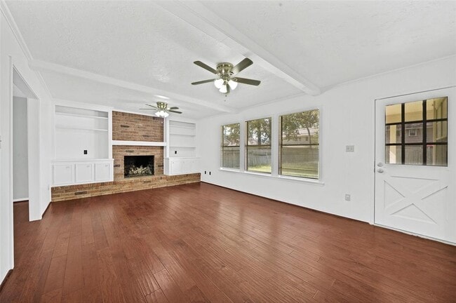 Living area with wood floors, built-in bookshelves, and gas log fireplace - 5703 Green Timbers Dr