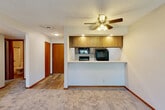 Located at 6521 Vine St in Lincoln, Nebraska, this single-floor residence offers two bedrooms and two bathrooms within a well-organized layout. The galley-style kitchen is efficiently designed with dark cabinetry, black appliances including a refrigerator, electric range, and built-in microwave, complemented by light countertops and wood-look flooring that adds a clean, modern touch. The open living area features plush carpeting, a textured ceiling, and a sliding glass patio door that invites natural light and provides outdoor access. Both bedrooms are carpeted and equipped with ceiling fans and natural light from well-placed windows. The primary bedroom offers a generous footprint with a built-in closet featuring bi-fold wood doors. The second bedroom similarly includes a large closet and a ceiling fan. The two bathrooms are straightforward and functional — one features a vanity with a single sink, wood cabinetry, and hard-surface flooring, while the other includes a full tub-shower combination. Warm wood trim accents are consistent throughout, providing visual cohesion. A connecting hallway ties the layout together, making this a practical and comfortable home.