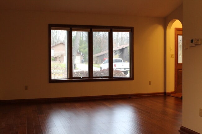 Amplia sala de estar con ricos pisos de madera y un gran ventanal que deja entrar luz natural. - 6235 Sunnywood Dr