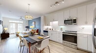 This thoughtfully designed single-floor residence offers an efficient and stylish living experience across a comfortable footprint. The open-concept layout seamlessly connects the kitchen, dining area, and living room, creating a cohesive and airy atmosphere throughout.

The kitchen is outfitted with crisp white cabinetry extending to the ceiling, stainless steel appliances including a range, microwave, dishwasher, and a large side-by-side refrigerator, complemented by white tile backsplash and light countertops. Light wood-style flooring flows throughout the main living areas, enhancing the bright and clean aesthetic.

The living room features a ceiling fan, light-toned walls accented by a bold blue feature wall, and French doors that open to a private balcony, inviting an abundance of natural light. The generously sized bedroom is carpeted for comfort, includes a ceiling fan, and benefits from large windows with outdoor views. A dedicated walk-in closet provides ample storage with multi-level shelving and hanging rods.

The full bathroom is finished with large-format tile flooring, a modern vanity with ample counter space, and a frameless glass shower. Additional conveniences include an in-unit laundry area and a utility room, rounding out a highly functional and modern living space.