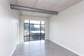 Located at 4661 Woodward Ave in Detroit's Midtown neighborhood, this single-floor unit blends industrial character with modern finishes throughout its well-organized layout. The kitchen serves as a central highlight, featuring white cabinetry, dark granite countertops, a full suite of stainless steel appliances including a range, microwave, dishwasher, and refrigerator, and pendant lighting above a peninsula that opens toward the living area. Light wood-style flooring runs through the kitchen and main living spaces, contributing to a clean, contemporary feel.

Exposed cylindrical ductwork runs along the ceiling, lending an industrial loft aesthetic that distinguishes the space from more conventional designs. The bedroom is carpeted and features tall ceilings that amplify the sense of volume, along with a sliding glass door that leads to a private balcony overlooking the Detroit cityscape—allowing for ample natural light and urban views.

The bathroom is finished with large-format tile flooring, white cabinetry for storage, and a full tub-shower combination. The overall layout is practical and efficiently organized, making good use of its single-floor footprint. The combination of modern fixtures and industrial architectural details gives the space a distinctive urban character well-suited to its Midtown Detroit location.