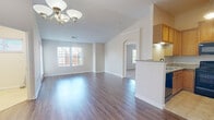 This two-story, 2-bedroom, 2-bathroom home offers a practical and comfortable layout across two levels. The main living floor features an open-concept kitchen and living room combination, where dark hardwood-style flooring runs throughout. The kitchen is outfitted with warm oak cabinetry, granite countertops, a stainless sink, and black appliances including a range, microwave, dishwasher, and refrigerator. A peninsula with a breakfast bar separates the kitchen from the bright, spacious living area, which is accented by a classic chandelier and multiple windows that fill the space with natural light. A door off the living area opens to a private outdoor deck with white railings and pleasant views of mature trees and the surrounding neighborhood. Carpeted stairs lead to the upper level, where both bedrooms are located. The generously sized primary bedroom features dual windows and plush carpet, accompanied by a private bathroom with oak vanity cabinetry and tile flooring, as well as a walk-in closet with wire shelving. A second bedroom and full bathroom complete the upper floor. Additional highlights include a dedicated laundry area with a water heater, multiple closets for storage, and an attached garage on the ground level.
