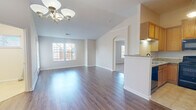 This two-story, 2-bedroom, 2-bathroom home offers a practical and comfortable layout across two levels. The main living floor features an open-concept kitchen and living room combination, where dark hardwood-style flooring runs throughout. The kitchen is outfitted with warm oak cabinetry, granite countertops, a stainless sink, and black appliances including a range, microwave, dishwasher, and refrigerator. A peninsula with a breakfast bar separates the kitchen from the bright, spacious living area, which is accented by a classic chandelier and multiple windows that fill the space with natural light. A door off the living area opens to a private outdoor deck with white railings and pleasant views of mature trees and the surrounding neighborhood. Carpeted stairs lead to the upper level, where both bedrooms are located. The generously sized primary bedroom features dual windows and plush carpet, accompanied by a private bathroom with oak vanity cabinetry and tile flooring, as well as a walk-in closet with wire shelving. A second bedroom and full bathroom complete the upper floor. Additional highlights include a dedicated laundry area with a water heater, multiple closets for storage, and an attached garage on the ground level.