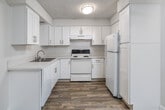 Located at 6560 Montezuma Rd in San Diego's College Area neighborhood, this one-bedroom, two-bathroom residence offers a thoughtfully designed single-floor layout. The entrance opens into a hallway with wood-style flooring and sliding closet doors, providing ample storage before leading into the main living areas. The spacious living room features plush carpeting, neutral walls, a textured ceiling, and a sliding glass door that opens onto a private balcony with outdoor views — filling the room with natural light. The kitchen is outfitted with crisp white shaker cabinetry, light countertops, a stainless steel sink, and white appliances including a range and refrigerator, all set over wood-style flooring. The generously sized primary bedroom is carpeted and includes natural light from a large window, along with access to a closet. Both bathrooms are finished with white vanity cabinetry, light countertops, wood-style tile flooring, and a shower-tub combination with sliding glass doors. Three closets distributed throughout the unit provide excellent storage capacity. The overall aesthetic is clean, bright, and move-in ready, with a consistent neutral palette and functional finishes throughout.